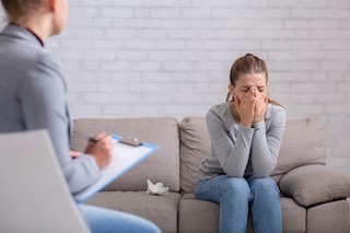 Mental health and psychological help concept. Young woman with depression on counseling session with therapist at clinic. PTSD disorder, anxiety, emotional problems treatment