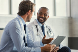 Doctor smiles while he explains medical detox to man in addiction treatment.
