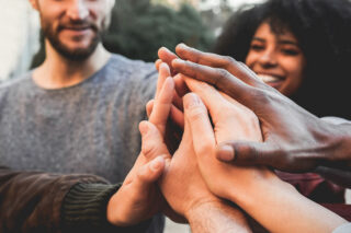 group in alcohol addiction recovery putting their hands together