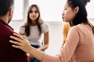 woman giving support to group member in therapy